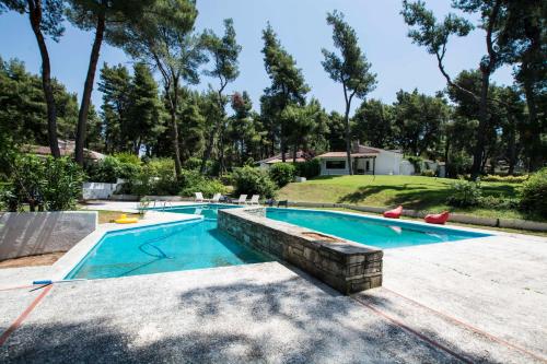 a swimming pool with a retaining wall in a yard at Villa Irini in Sani in Sani Beach