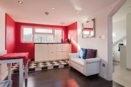 a kitchen with red walls and a chair and a table at Studio flat 15 min from Greenwich ( en-suite) in Plumstead