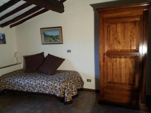 サン・ジミニャーノにあるPodere Il Caggio Roomsのベッドルーム1室(ベッド1台付)、木製のドア