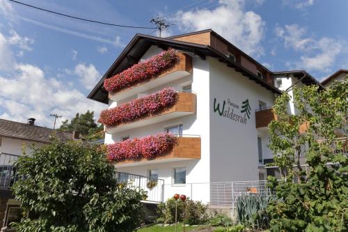 a white building with red flowers on it at Pension Waldesruh in Tarrenz