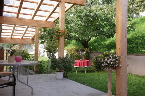 a wooden pergola with a table in a garden at Pension Waldesruh in Tarrenz