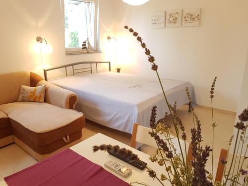 a bedroom with a bed and a couch and a table at Olive Apartments in Ugljan