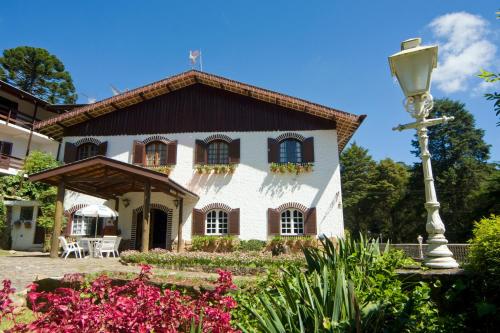 a white house with a black roof and a street light at Terrazza Hotel in Campos do Jordão