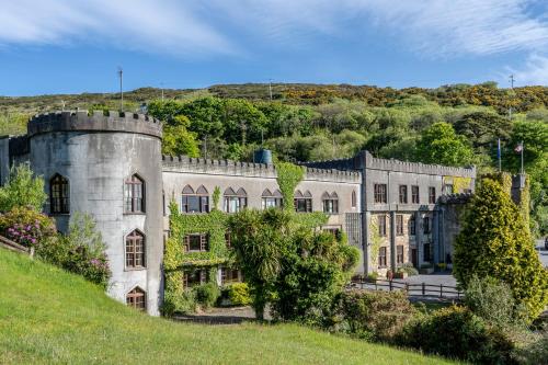 an old castle on a hill with trees at Abbeyglen Castle Hotel in Clifden