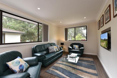 a living room with two couches and two windows at Marbles on Lovedale in Lovedale