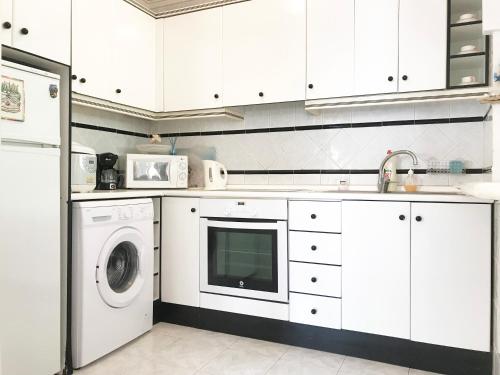 a kitchen with white cabinets and a washer and dryer at Apartamento CalarAlto 7 in Torrevieja