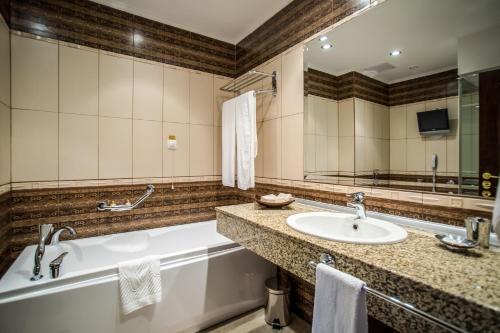 a bathroom with a tub and a sink at Hotel Palace Marina Dinevi in Sveti Vlas