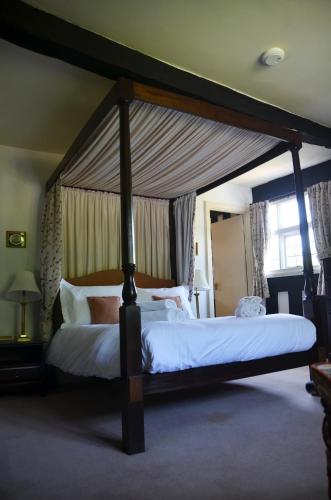 a bedroom with a large canopy bed with white sheets at Rhydspence in Hay-on-Wye