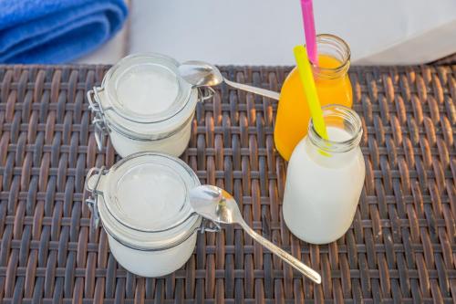 quatre récipients en verre contenant du lait et une boisson sur une table dans l'établissement Eiriana Luxury Suites, à Plaka Milou