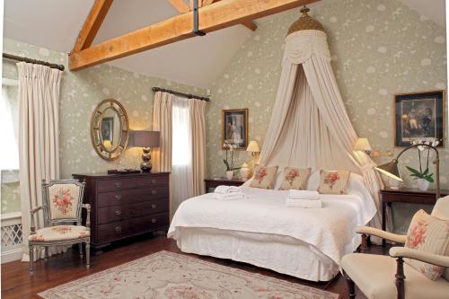 a bedroom with a canopy bed and a chair at Cope Cottage in Bruern