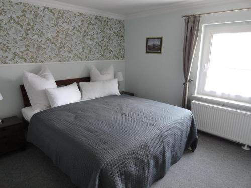 ein Schlafzimmer mit einem Bett mit weißen Kissen und einem Fenster in der Unterkunft Cottage Ferienwohnung mit Seeblick in Caputh