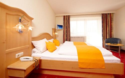 a bedroom with a large bed with yellow pillows at Alpenhotel Rieger in Mittenwald