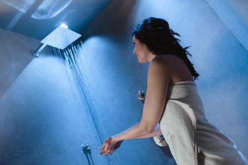 a woman is spraying herself with a shower at Hotel Tiefenbrunn Gardensuites & Breakfast in Lana