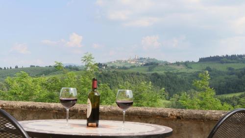 a table with a bottle of wine and two glasses at The Best View San Gimignano Apartments in San Gimignano