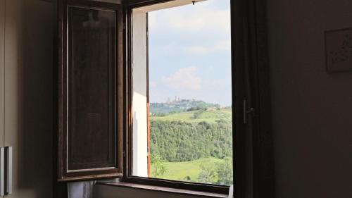 a window with a view of a green hill at The Best View San Gimignano Apartments in San Gimignano