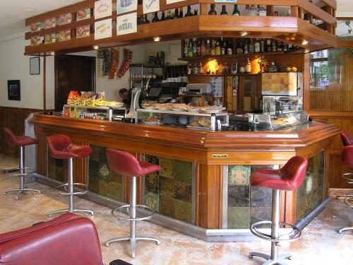 un restaurante con barra con taburetes rojos en Hotel Rico, en Luarca