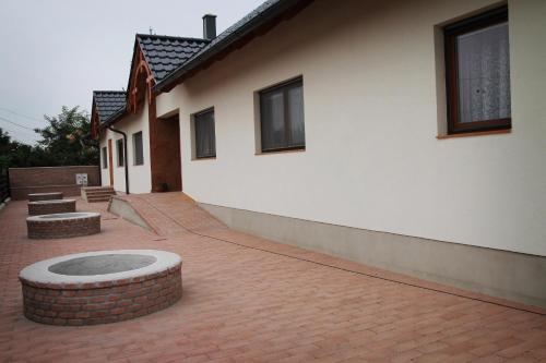 a building with a brick courtyard with two benches at Hanság Vendégház in Kapuvár