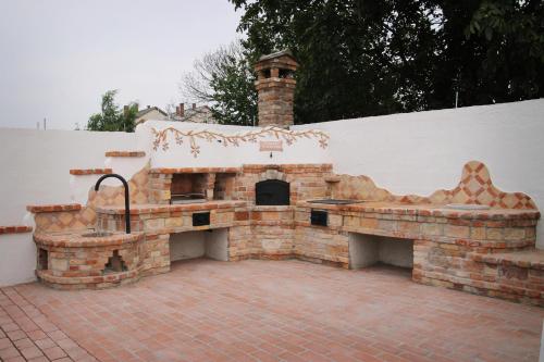 an outdoor grill with a brick fireplace in a backyard at Hanság Vendégház in Kapuvár