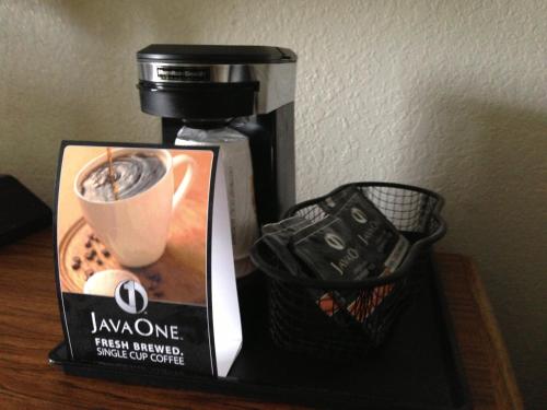 a coffee maker with a sign next to a cup of coffee at Super 8 by Wyndham Newport News/Jefferson Ave. in Newport News