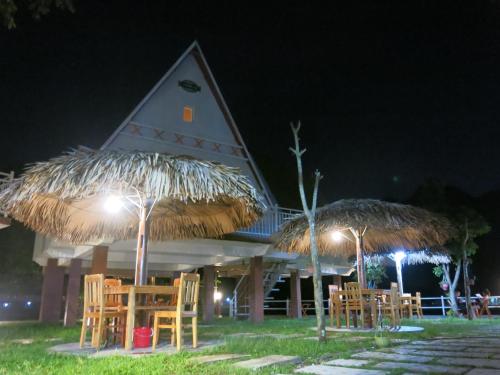 a building with chairs and umbrellas at night at Carambola Bungalow in Phong Nha