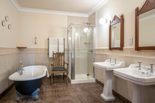 a bathroom with two sinks and a tub and a shower at Abbeyglen Castle Hotel in Clifden