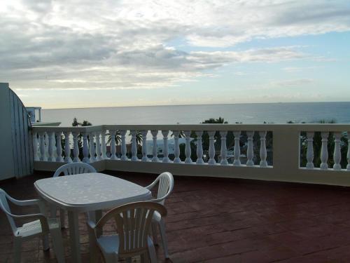 a table and chairs on a balcony overlooking the ocean at Las Palmeras RIKI R in Boca Chica