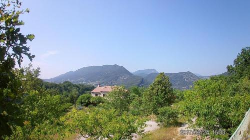 a house on a hill with mountains in the background at La Drugère - Gîtes et Roulottes in Nyons