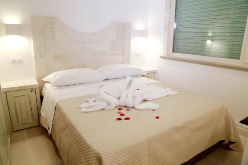 a bed with white towels and red rose petals on it at Villa Angelina in Selva di Fasano