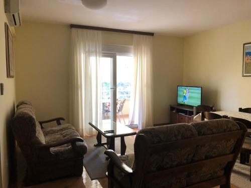 ein Wohnzimmer mit einem Sofa und einem TV in der Unterkunft Apartment Sanja in Baška Voda