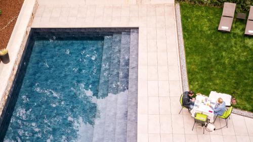 a man and woman sitting at a table next to a swimming pool at Flora Hotel & Suites in Merano