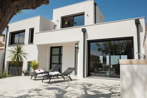 a white house with two chairs on a patio at Villa La Perle de Thau in Sète
