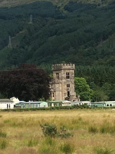 an old stone tower with a train in a field at Swift bordeaux 24 in Dunoon