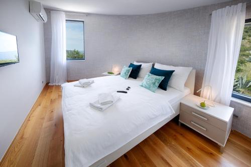 a large white bed in a room with windows at Villa Periska Komiža in Komiža