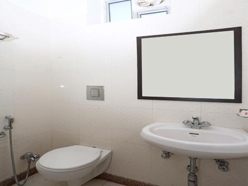a bathroom with a toilet and a sink and a mirror at Hotel Shivam in Ajmer
