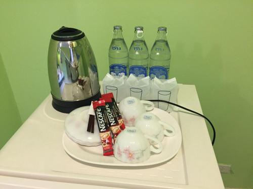 a table with a tray with a tea pot and bottles of soda at PPS Home in Surin