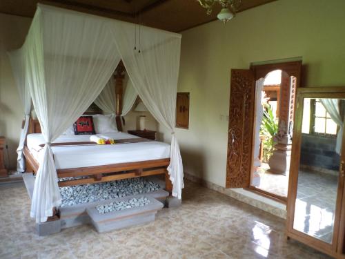 a bedroom with a bed with a mosquito net at Ala's Green Lagoon in Ubud