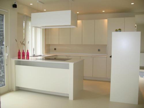 a white kitchen with a stove and a refrigerator at Duinpaviljoen in Koksijde