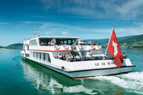 a white boat with a red flag on the water at City Hotel Biel Bienne Free Parking in Biel