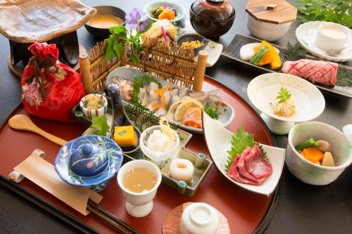 a table topped with plates and bowls of food at Kurokawa Onsen Ryokan Ichinoi in Minamioguni