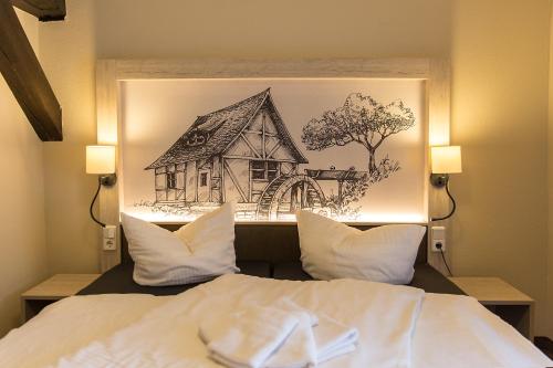 a drawing of a house is above a bed at Hotel Garni Mühlenhof in Wusterhausen