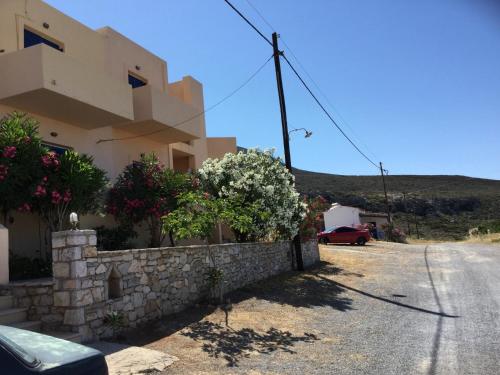 a house with a stone wall and a car parked next to it at Eugenia travasarou sea view appartments in Dhiakofti
