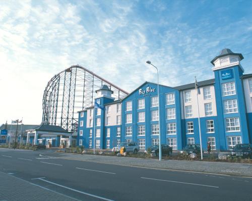um grande edifício azul com uma montanha-russa ao fundo em The Big Blue Hotel - Blackpool Pleasure Beach em Blackpool