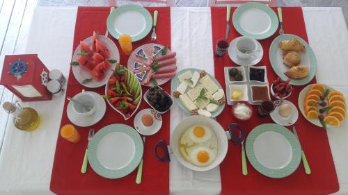 einen Tisch mit Teller mit Lebensmitteln auf einem roten und weißen Tischtuch in der Unterkunft Narcicegi Hotel in Cıralı