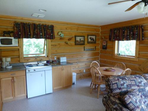 a kitchen with wooden walls and a table and a kitchen with a sink at Mica Mountain Lodge & Log Cabins in Tete Jaune Cache