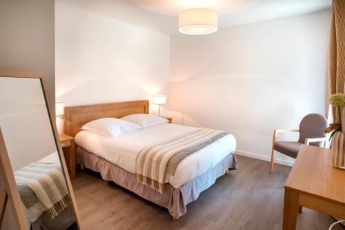 een slaapkamer met een bed, een bureau en een spiegel bij Domitys Les Sarments Blonds in Montpellier