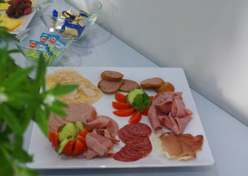 a white plate with meat and vegetables on a table at Fast Lane Hotel in Barweiler