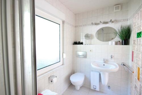 ein Bad mit einem Waschbecken, einem WC und einem Fenster in der Unterkunft Bungalow am Schmachter See by Rujana in Binz
