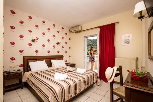 a bedroom with a bed and a woman looking out the window at Philoxenia Inn in Limenas