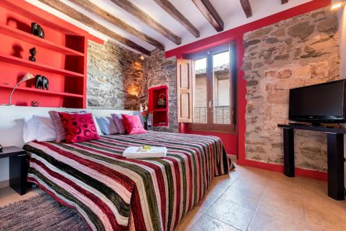 - une chambre rouge avec un lit et une télévision dans l'établissement Hotel Cal Llop, à Gratallops