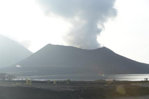 a mountain with smoke coming out of it next to a body of water at Gazelle International Hotel in Kokopo